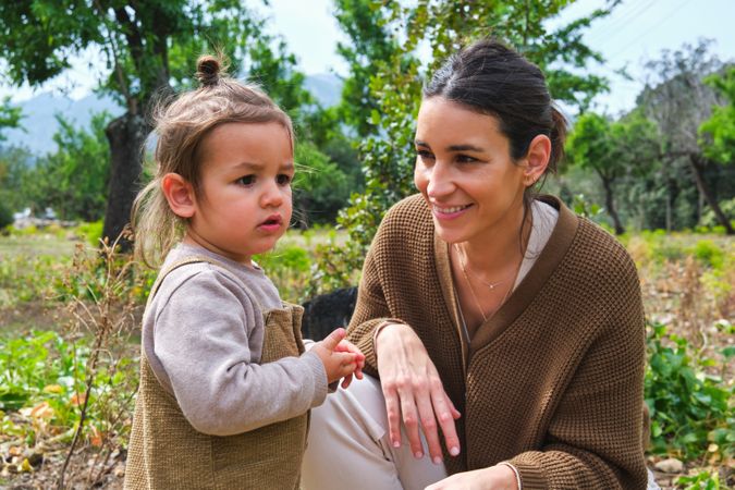 Smiling mother and cute daughter spending time in verdant park