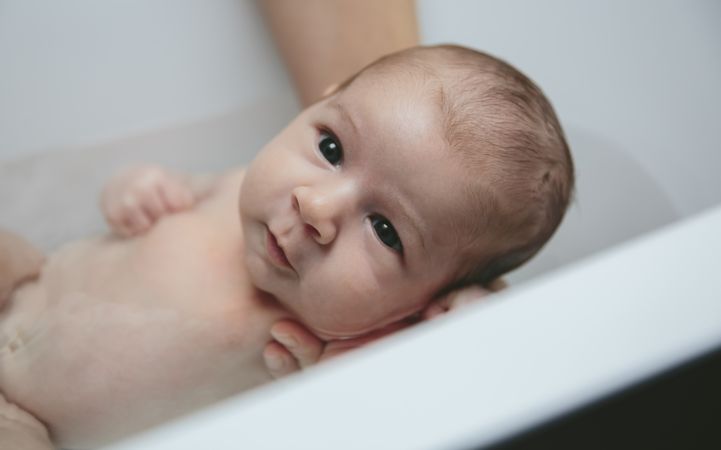 Newborn in the bathtub held by her mother