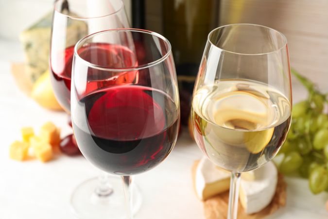 Grape, bottles and glasses with wine on plain background, close up