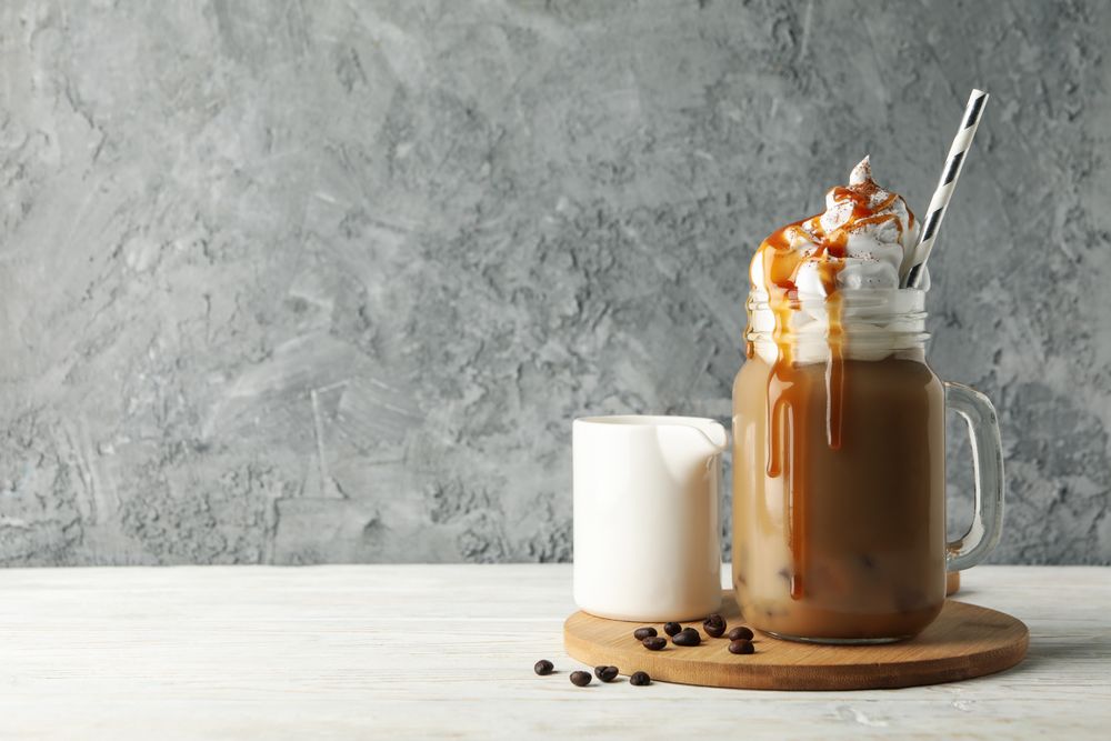 Iced coffee with poured cream on wooden background