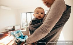 Cropped shot of a woman carrying her baby in a baby sling carrier at home 5rzz25