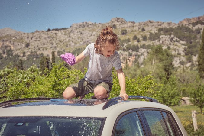 Little boy on car on sunny day