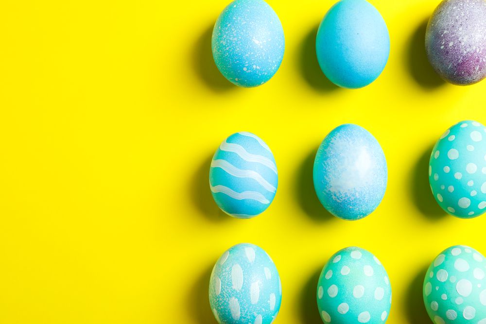 Flat lay composition with colorful easter eggs on yellow background. Space for text