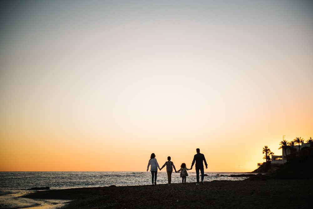 Silhouette of family holding hands at sunset