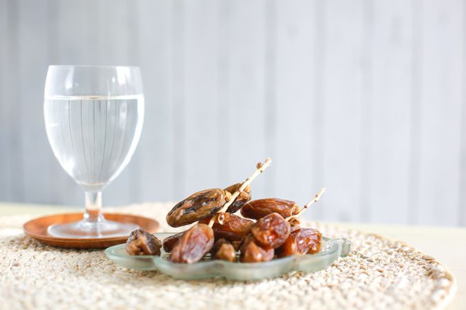 Dates on a Plate With a Glass of Fresh Water