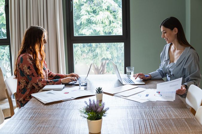 Positive colleagues working on laptop in light workspace
