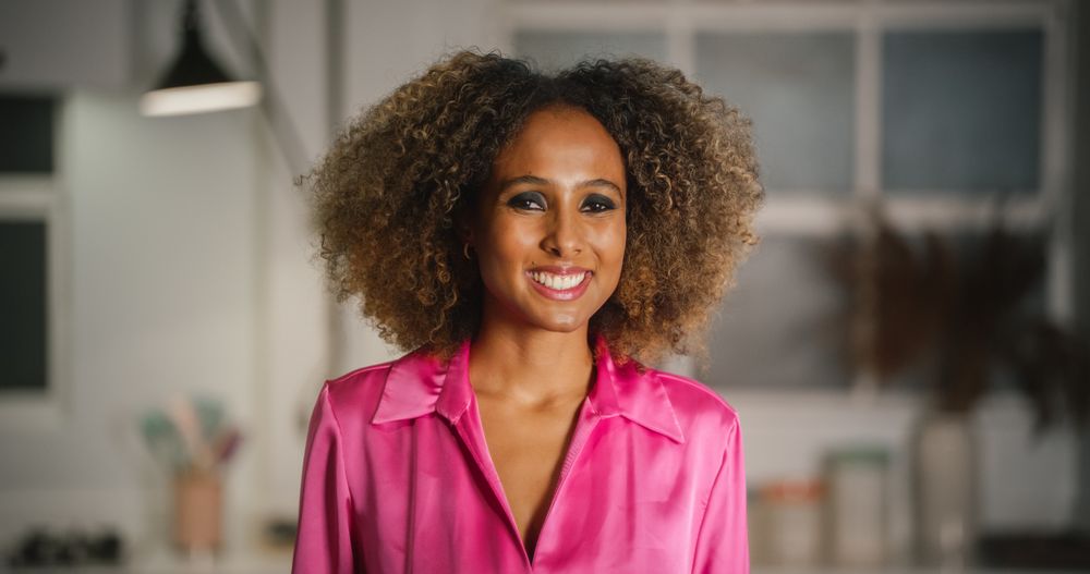 Portrait of Black Female with Curly Hair Looking at Camera and Smiling.