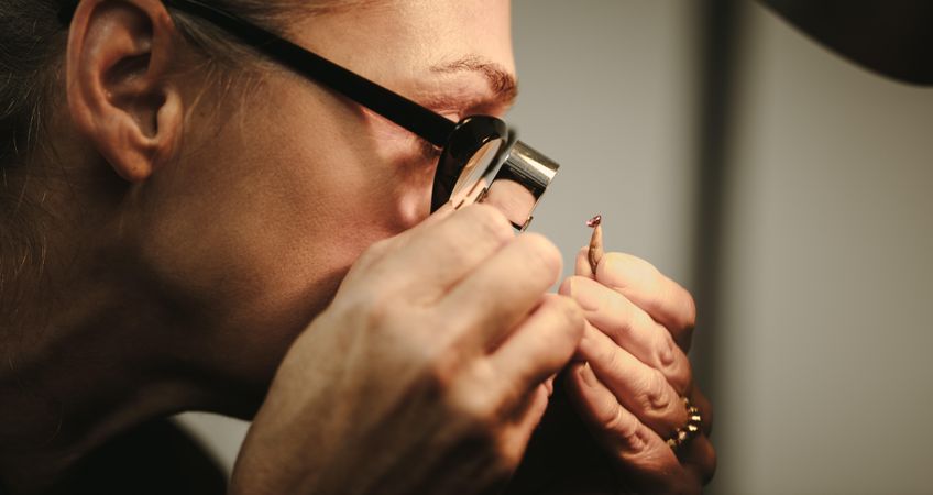 Closeup of woman goldsmith checking quality of a diamond