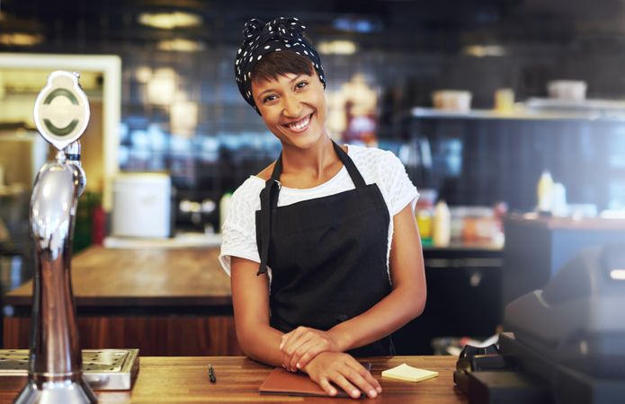 Black woman standing and smiling behind bar