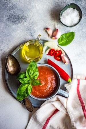 Looking down at cup of gazpacho soup with basil, garlic, pepper and olive oil