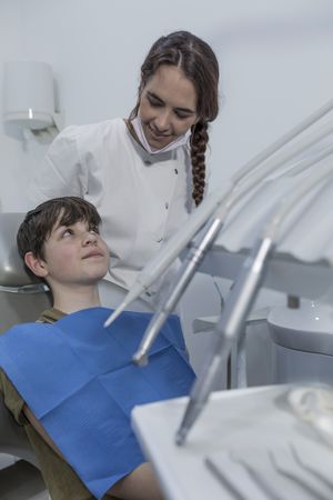 A teenage boy is being examined by a professional female dentist