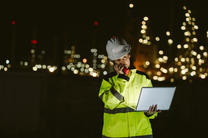 Night work at an oil refinery, engineer worker talking with walkie talkie