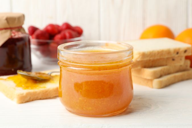 Composition with apricot jam on wooden background. Sweet breakfast