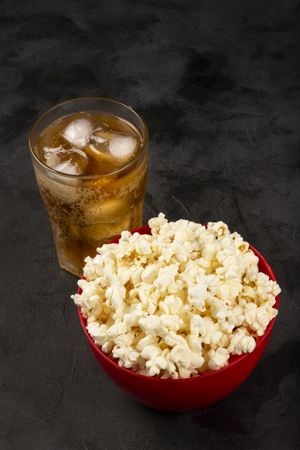 Bowl with salted popcorn and soda on the table.