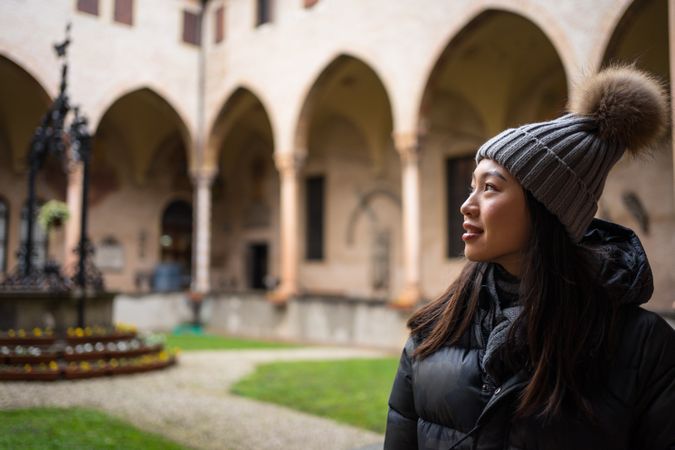 Young Asian female on vacation in warm clothing having excursion at historical temple