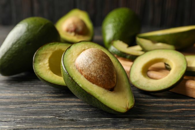 Board and avocado on wooden background, close up