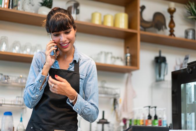 Female in apron working in cafe taking a phone call