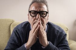 Mature man praying or thinking deeply at home.