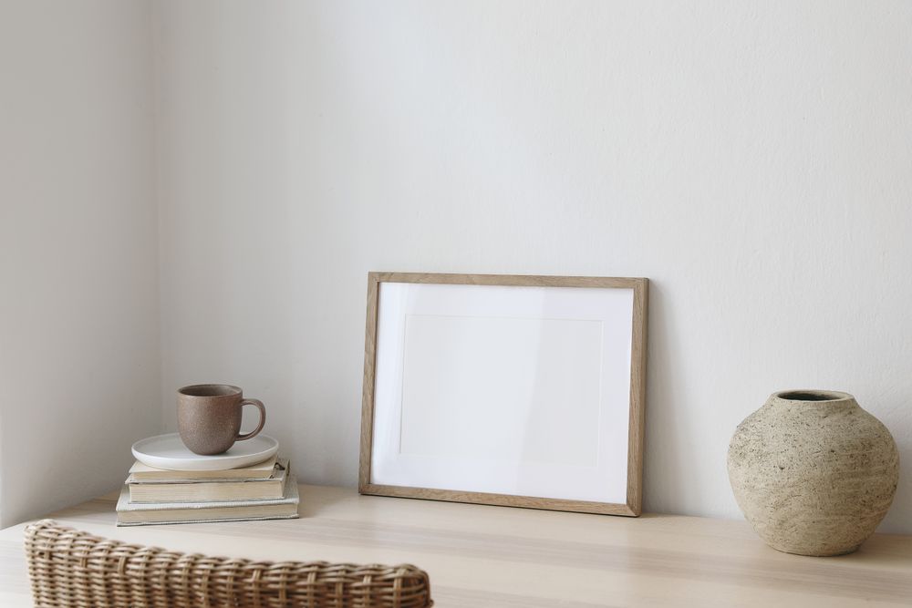 Poster frame on neutral table with vase and mug of coffee