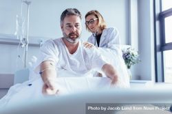 Doctor examining mature man in hospital bed 42M9K5