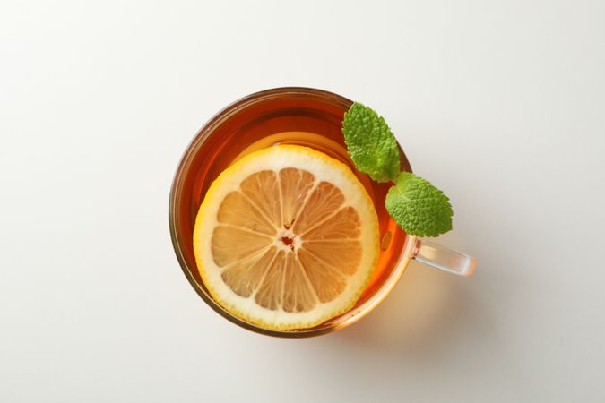 Cup of tea, mint and lemon on plain background, top view