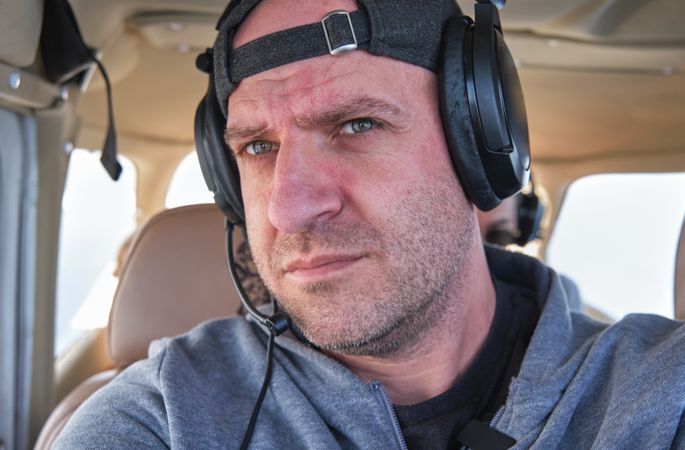 Crop serious captain in headphones sitting in flying airplane