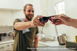 Man standing in kitchen at home toasting wine with a friend 5alAo0