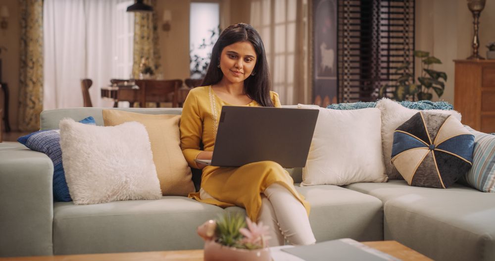 Indian Woman Using Laptop at Home, Focused on Remote Work Tasks and Managing Team.