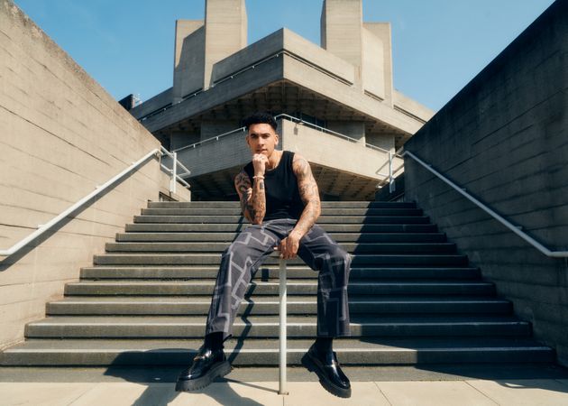 Man in graphic trousers sitting on rail in center of stairs