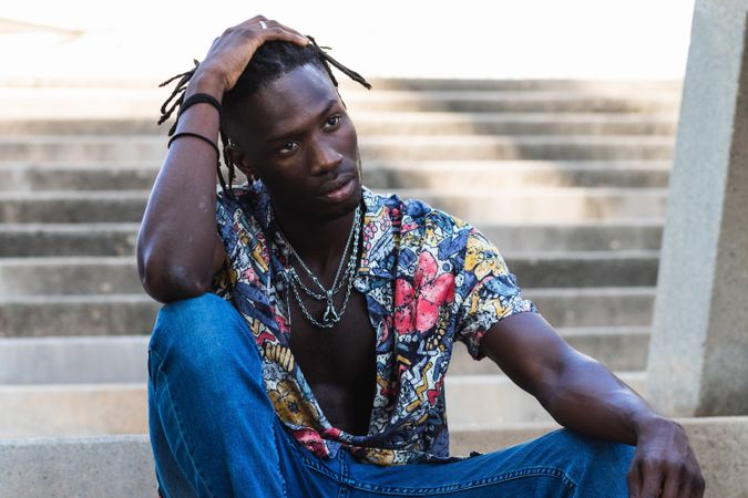 Stylish Black hipster man sitting on stairs in city