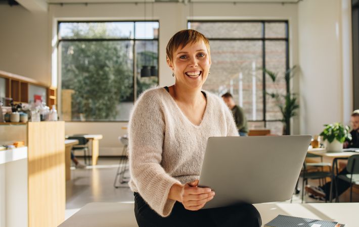 Smiling entrepreneur in co-working space with laptop