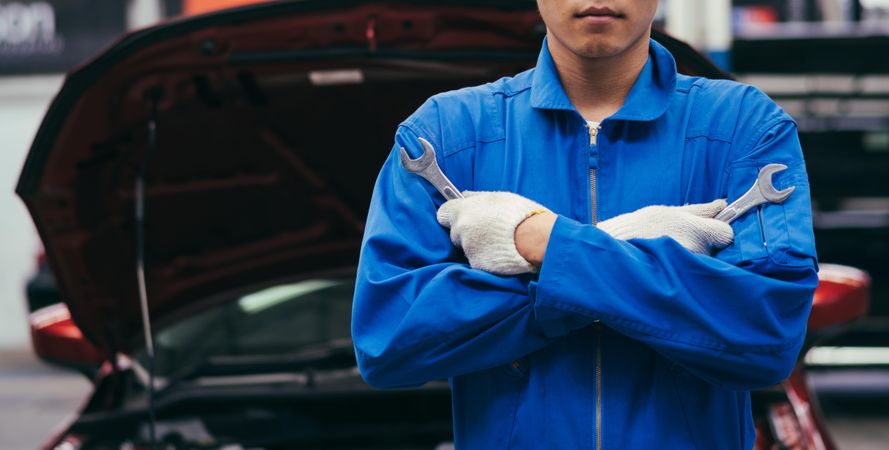 Banner of male mechanic holding wrench in front of car