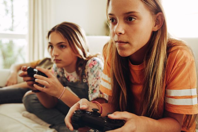 Close up of two teenage girls playing video game holding joysticks