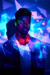 Black man with headphones standing in neon lights