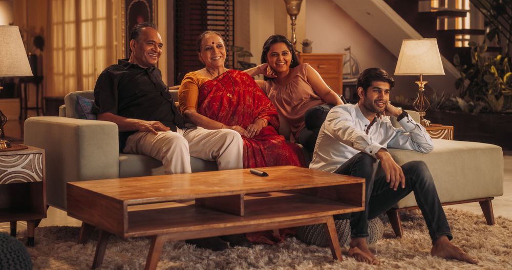 Portrait of Happy Indian Family Enjoying Movie Playing on TV at Home Together.