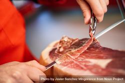 Close up of female hands in butcher shop slicing ham 4B6de4