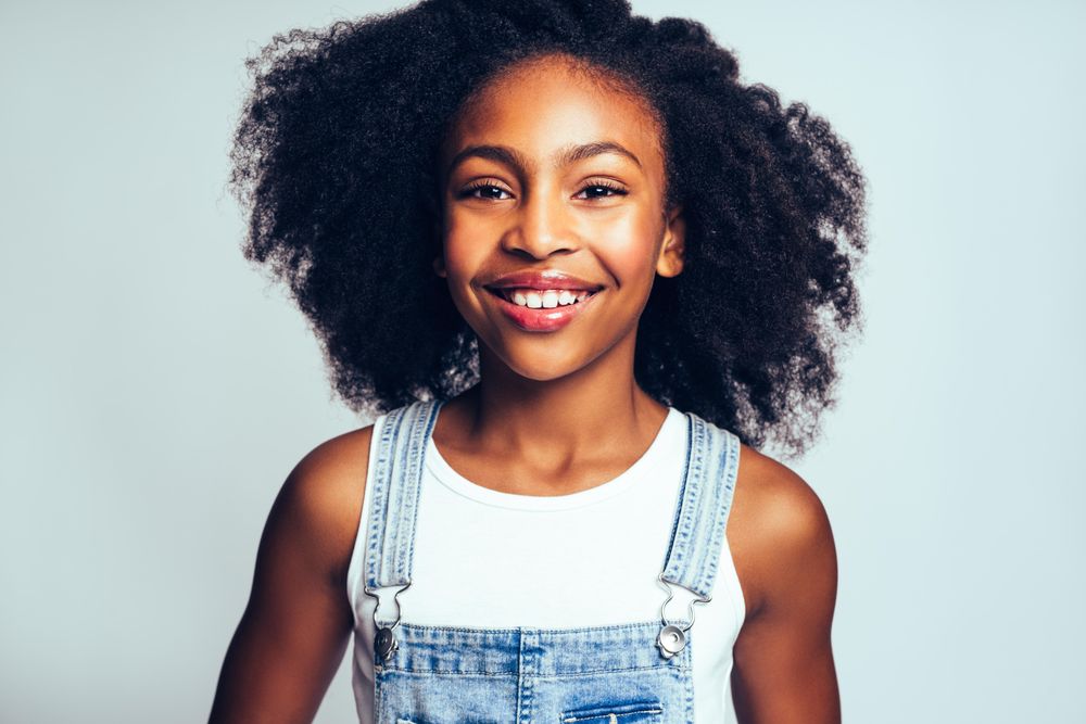 Studio portrait of happy girl smiling in jean overalls