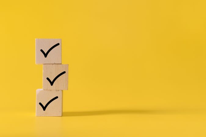 stack wooden blocks with checkmark symbol isolated on yellow background