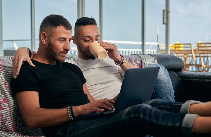 Happy gay couple using laptop at home