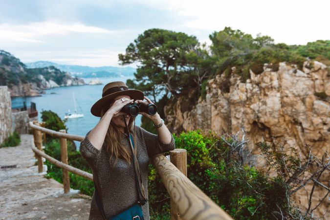 Woman with binocular on coastal walkway