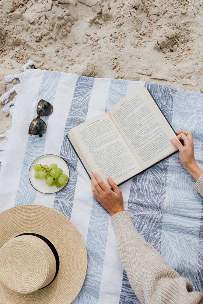 Top view of person reading a book on a picnic mat