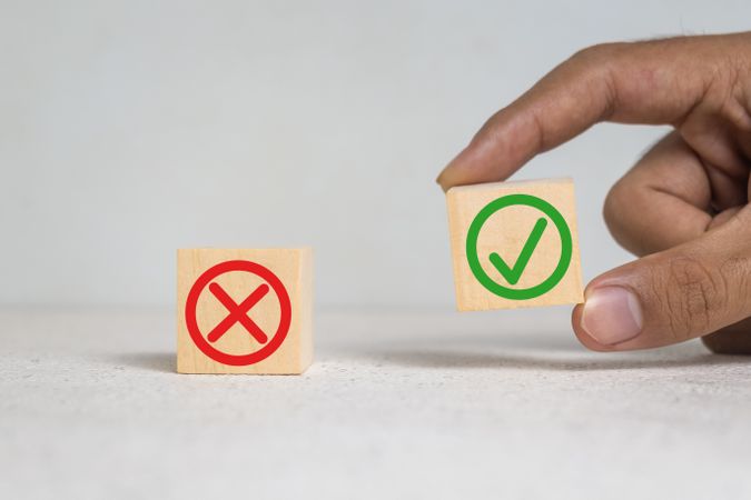 red and green cross and check sign symbol on wooden blocks on light background