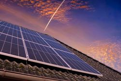 Solar panels producing clean energy on a roof of a residential house during sunset.