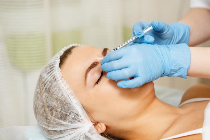 Cosmetologist at med spa injecting botox in female client