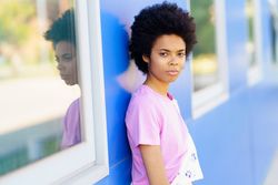 Calm woman looking at camera and leaning on blue building