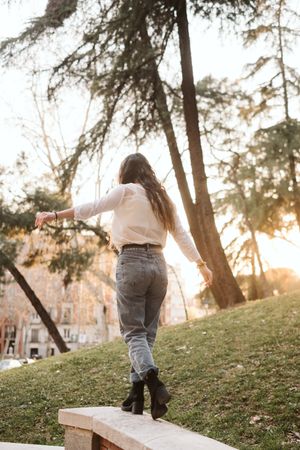 Anonymous young woman walking on border in park
