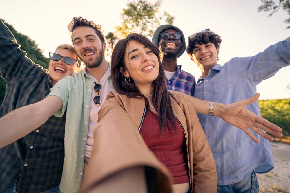 Happy young woman taking a selfie with her diverse group of friends outdoors.