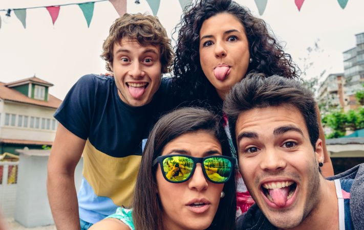 Friends outside sticking out tongue at camera