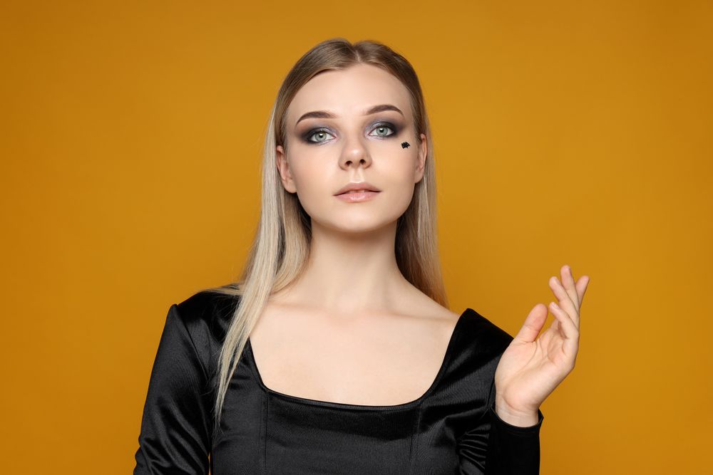 Concept of Halloween, young woman on yellow background
