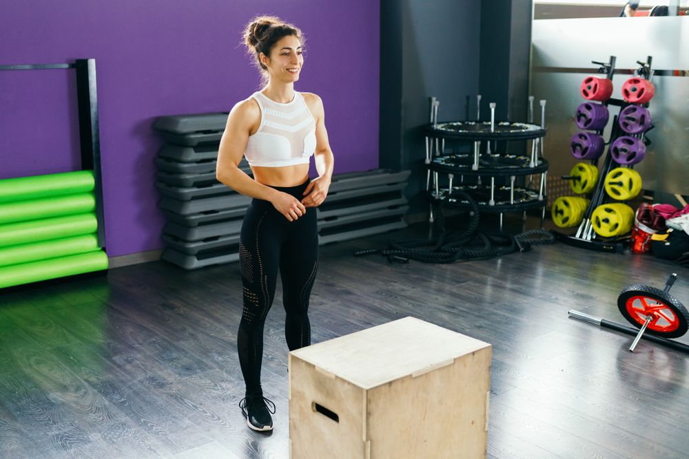 Woman standing in front of a box preparing to jump